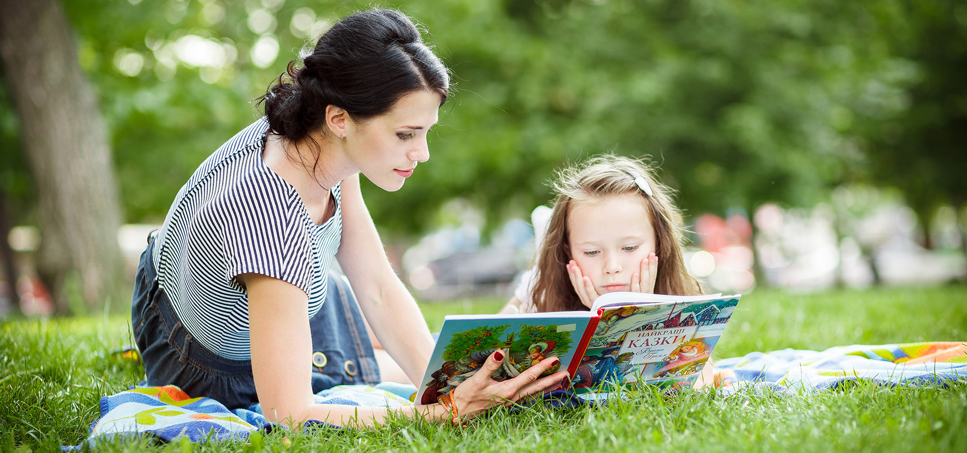 Mother reading to her daugther in the park